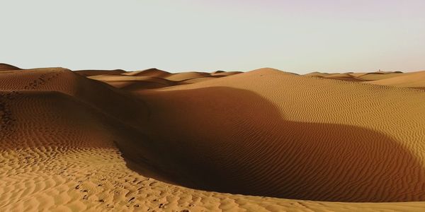 Sand dunes in desert against clear sky