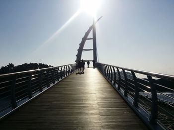 Footbridge over water against clear sky