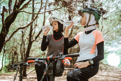 Female cyclist drinking water at park