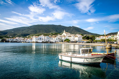 Boats moored at river against town and mountains