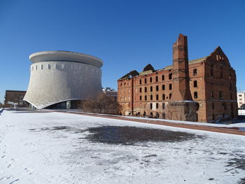 Snow covered buildings against clear blue sky