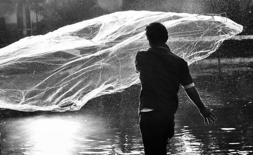 Rear view of man standing by lake