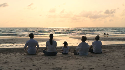 Rear view of people sitting on beach