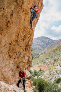 Faceless fearless active female climber ascending on cliff during mountaineering in summer day