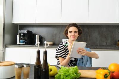 Portrait of smiling young woman using mobile phone while sitting at home