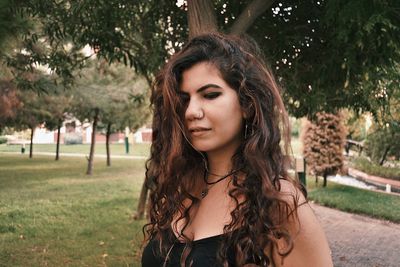 Portrait of beautiful young woman standing against trees