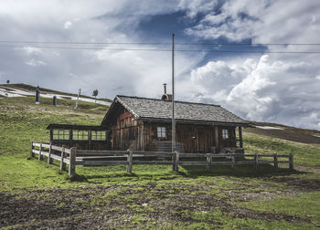 House on mountain against cloudy sky