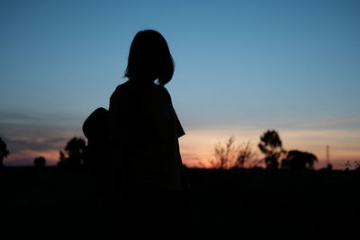 Silhouette woman standing on field against clear sky during sunset