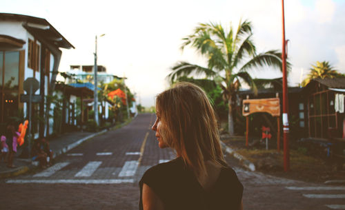 Rear view of woman on street against clear sky during sunset