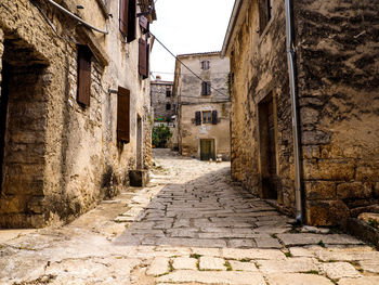 Walkway amidst houses against sky