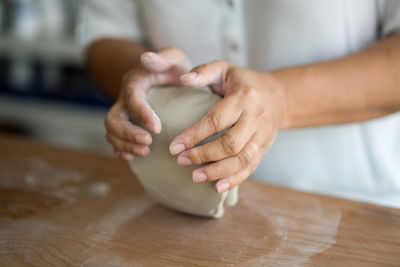 Midsection of woman kneading clay on table in workshop