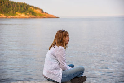 Woman sitting on rock against sea