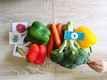 Cropped hand of child touching vegetables on wooden table
