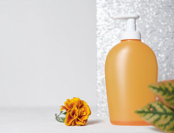 Close-up of orange rose on white table