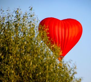 Close-up of red heart shape balloon against sky