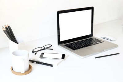 Coffee cup and laptop on table