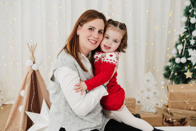 Portrait of smiling young woman holding christmas tree