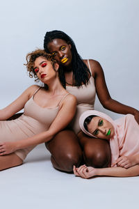 Portrait of women sitting against white background