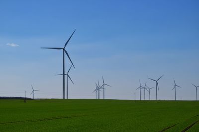 Windmills on field against sky