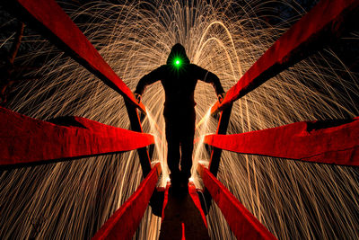 Rear view of man standing on illuminated red light