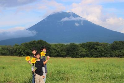 Portrait of friends standing on field against mountains