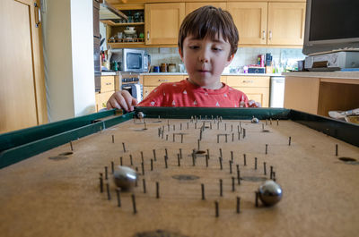 Cute boy playing bagatelle at home
