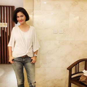 Portrait of smiling young woman standing against wall