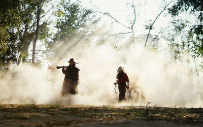 People standing on field against trees in forest