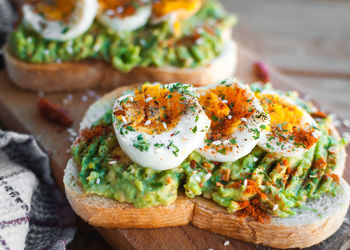 Close-up of avocado and egg toast with herbs and seasonings, on cutting board