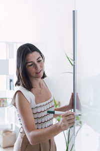 Young businesswoman writing on whiteboard in office