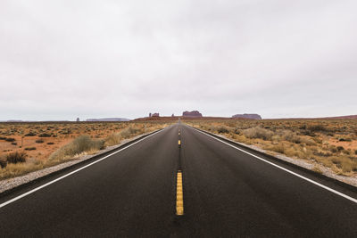 Road leading towards landscape against sky