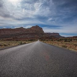 Empty road by mountains against sky