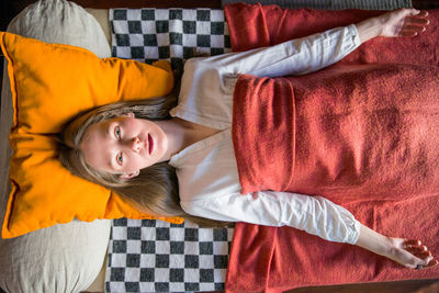 High angle portrait of woman relaxing on bed at home