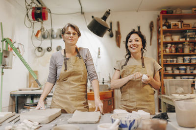 Happy entrepreneur with colleague working together at ceramics workshop