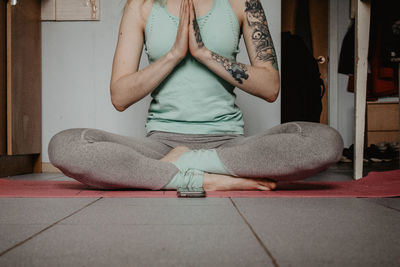 Low section of woman meditating while sitting at home