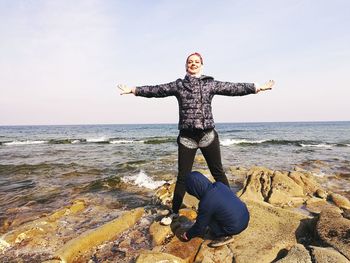 Full length of man with arms raised on beach against sky