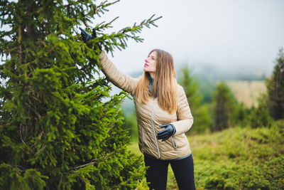 Full length of young woman standing by tree