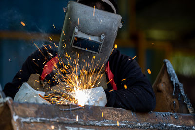 Welder in iron mask helmet welds steel welding, industrial worker at the factory welding steel 