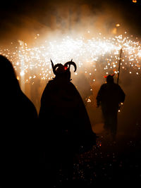 Rear view of woman standing on road at night