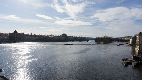 Bridge over river by buildings in city against sky