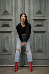 Portrait of young woman standing against wall