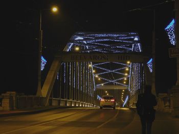 Illuminated bridge in city against sky at night