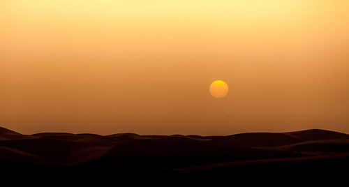 Scenic view of silhouette mountain against orange sky