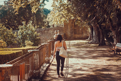 Rear view of woman standing on railing against trees