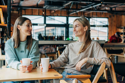 Young woman using mobile phone while sitting in cafe