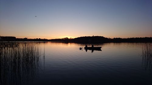 Silhouette boat in lake against sky during sunset