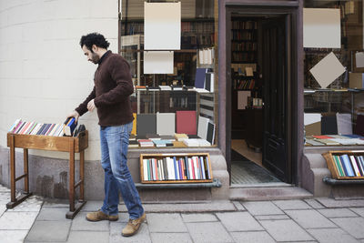 Customer searching book while standing on sidewalk outside library