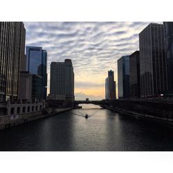 City at waterfront against cloudy sky