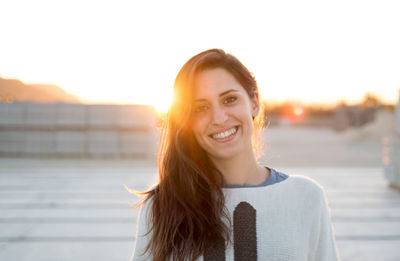 Portrait of smiling young woman standing against sky during sunset