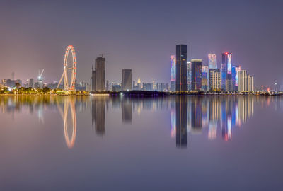 Reflection of illuminated buildings in city against sky